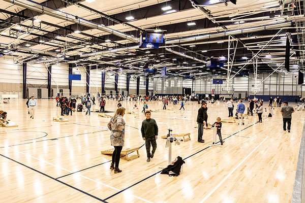 Inside of AtTheGrounds sports arena with kids playing cornhole